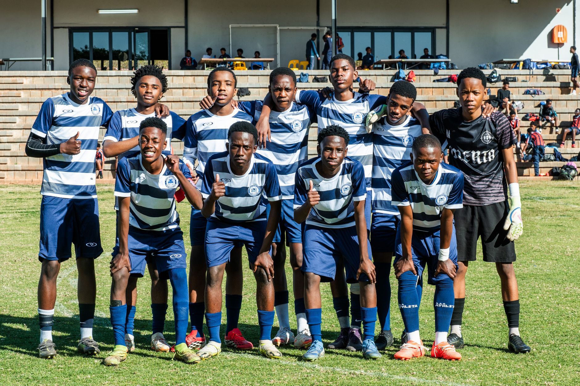 A group of teenage soccer players posing on a grassy football field.