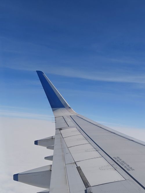 Free Captivating view from an airplane window showcasing the wing against a bright blue sky. Stock Photo