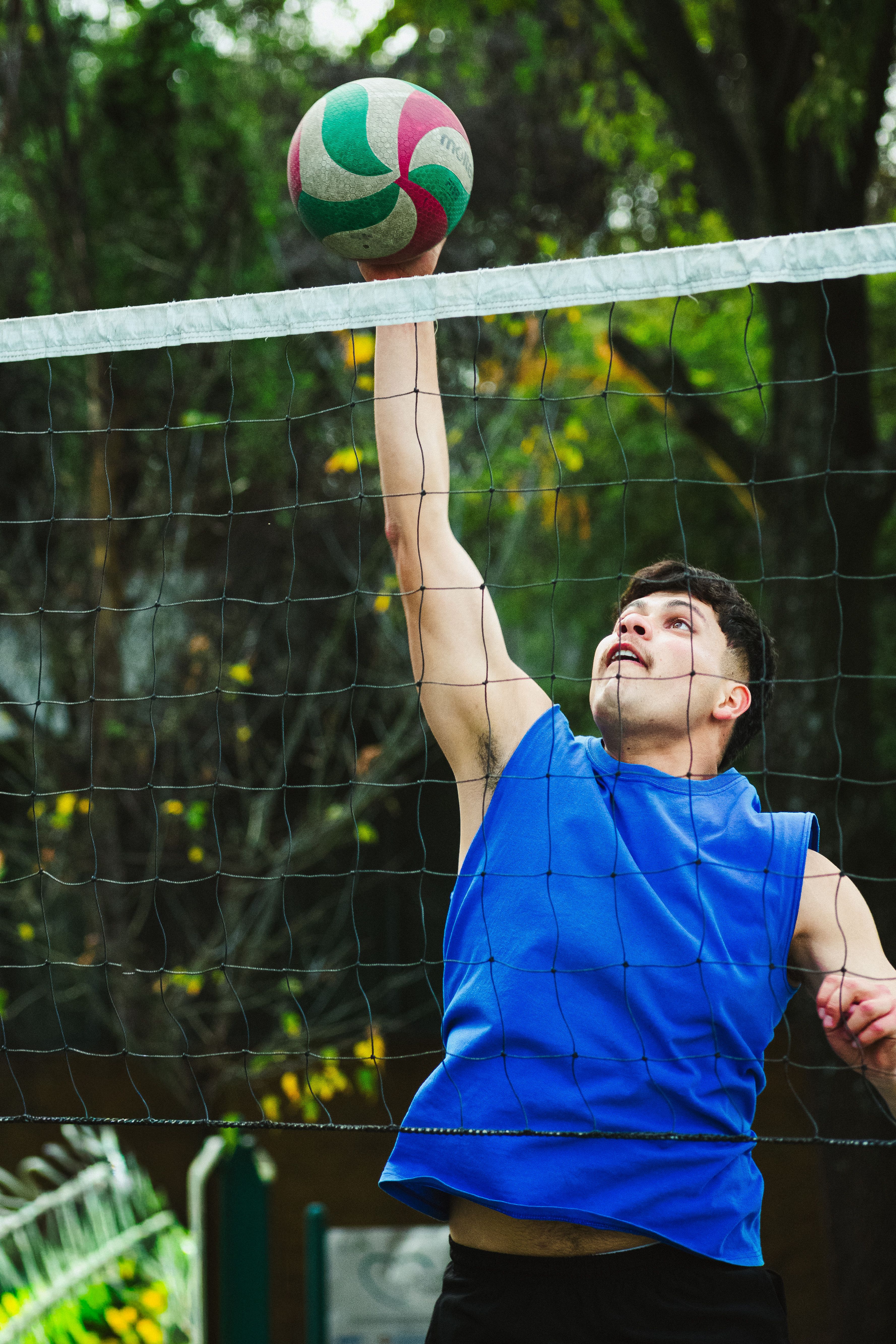 Young man jumping high to spike a volleyball during an outdoor match in Mexico City.