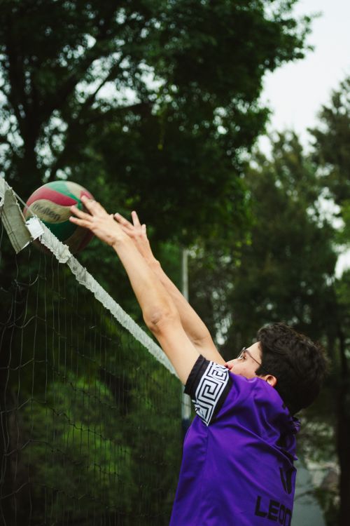 Free An energetic volleyball player in action during a match, reaching for the ball over the net in Ciudad de México. Stock Photo