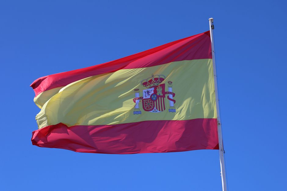 Vibrante bandera española ondeando bajo un claro cielo azul simbolizando el orgullo nacional.