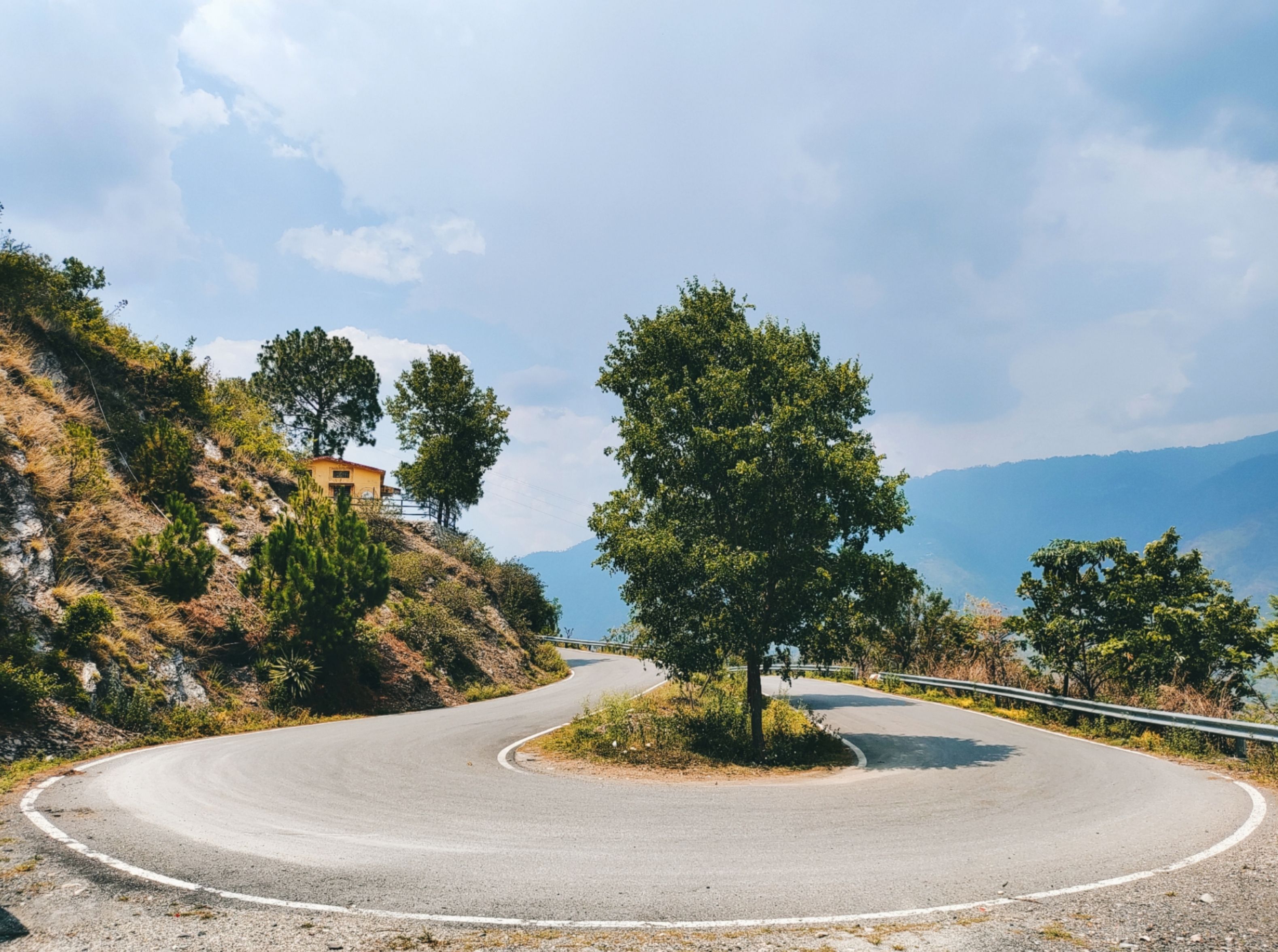 Hairpin bend on the tea-estate road above Adimali, with Kochi-registered car parked at a viewpoint