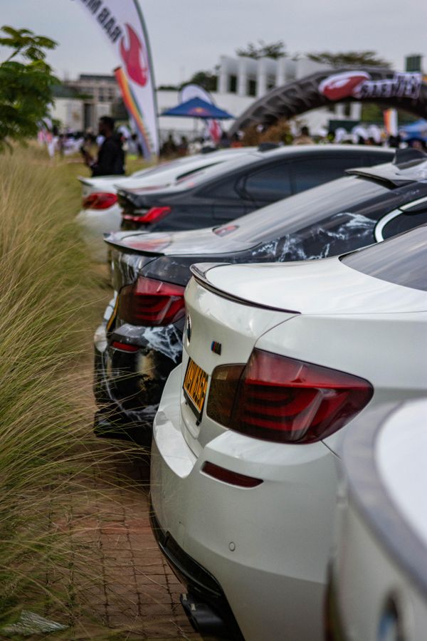 Fileira de carros de luxo em uma exposição automobilística ao ar livre, apresentando diversos modelos de automóveis.