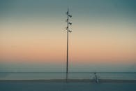 日落时分，在五彩缤纷的万里无云的天空下，一个匿名者沿着孤柱附近的海滨骑自行车，这是他的侧视图