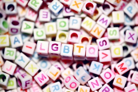 Vibrant rainbow-colored beads spelling LGBTQ amidst a jumble of letters, symbolizing diversity and identity.