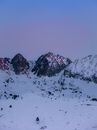 黄昏时分，白雪覆盖的山峰展现出宁静的冬季景观