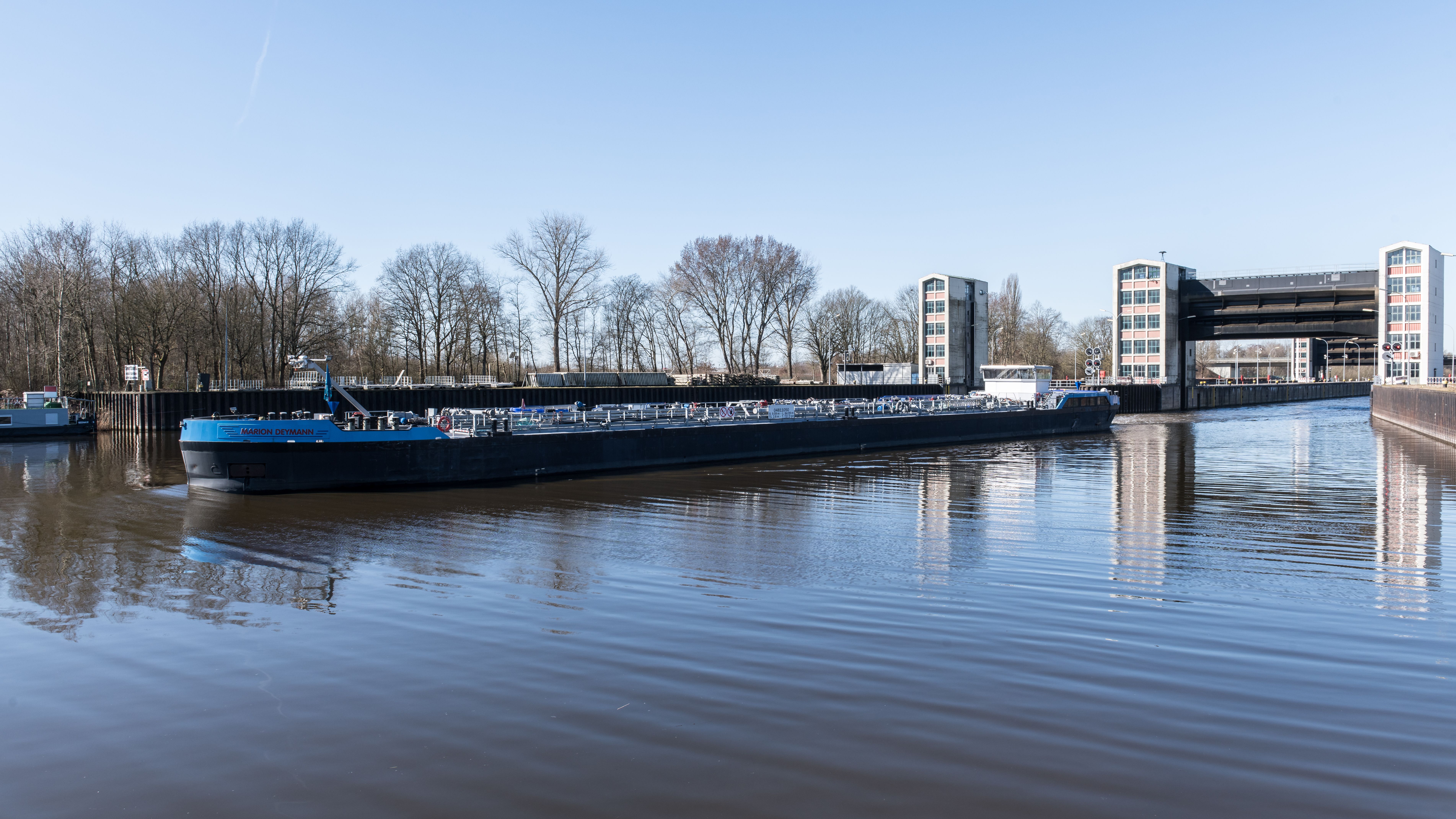 Illustrative photograph: A cargo ship navigates through the Geesthacht floodgate on a clear day in Schleswig-Holstein, Germany.