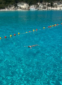 A person floating peacefully in clear blue waters near a scenic coastline.