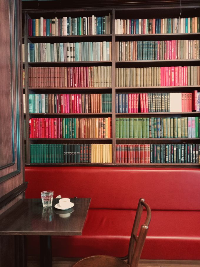A corner seat beneath a wall of colour-sorted books, photo by Fidan Nazim qizi on Pexels