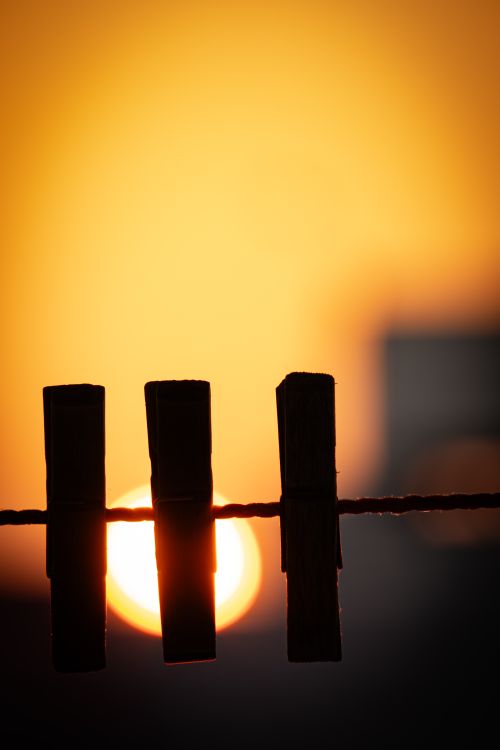Free Three clothespins on a line silhouetted by a vivid sunset sky, evoking warmth and simplicity. Stock Photo