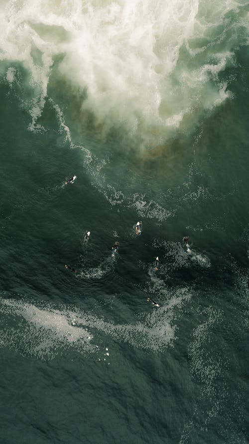 Вид с воздуха на людей, занимающихся серфингом на морских волнах