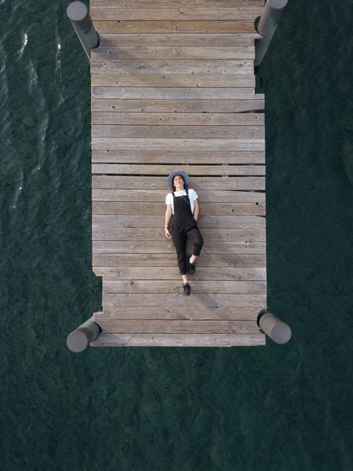 Woman In Black Overall Lying Down on Wooden Dock