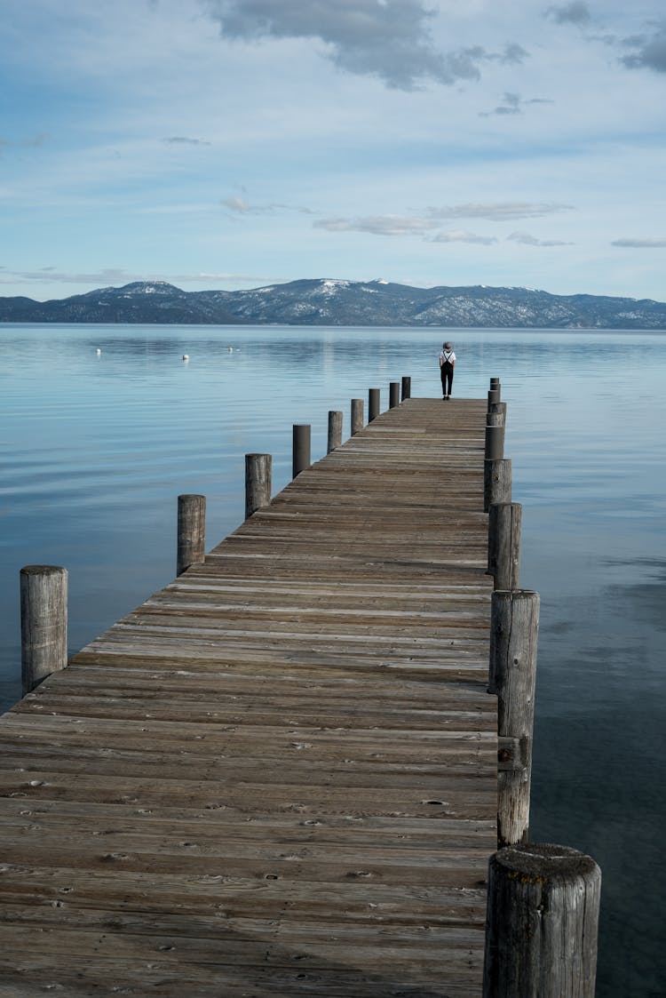 Lonely Person On Pier In Mountain Lake