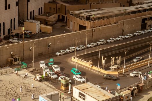 A bustling street scene near Masjid Al-Haram with cars and pedestrians, seen from above.