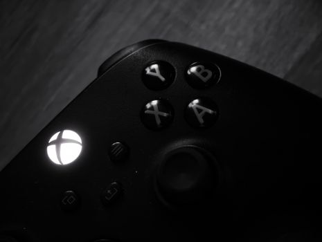Monochrome close-up of a gaming controller highlighting buttons and logo.