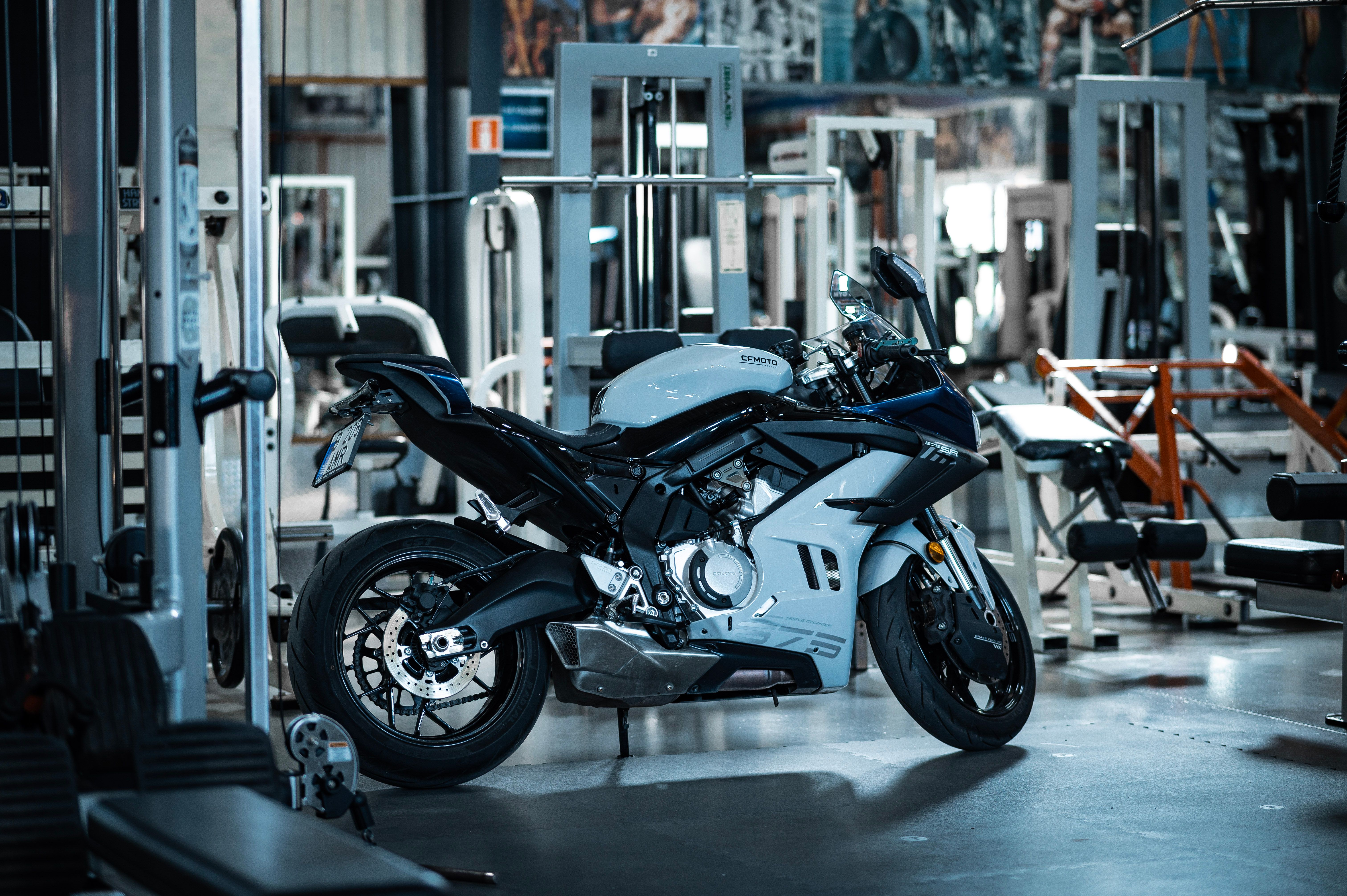 Alignement de motos chinoises 2026 (CFMoto, Voge, QJMotor) devant une concession européenne, cadrage large en lumière naturelle