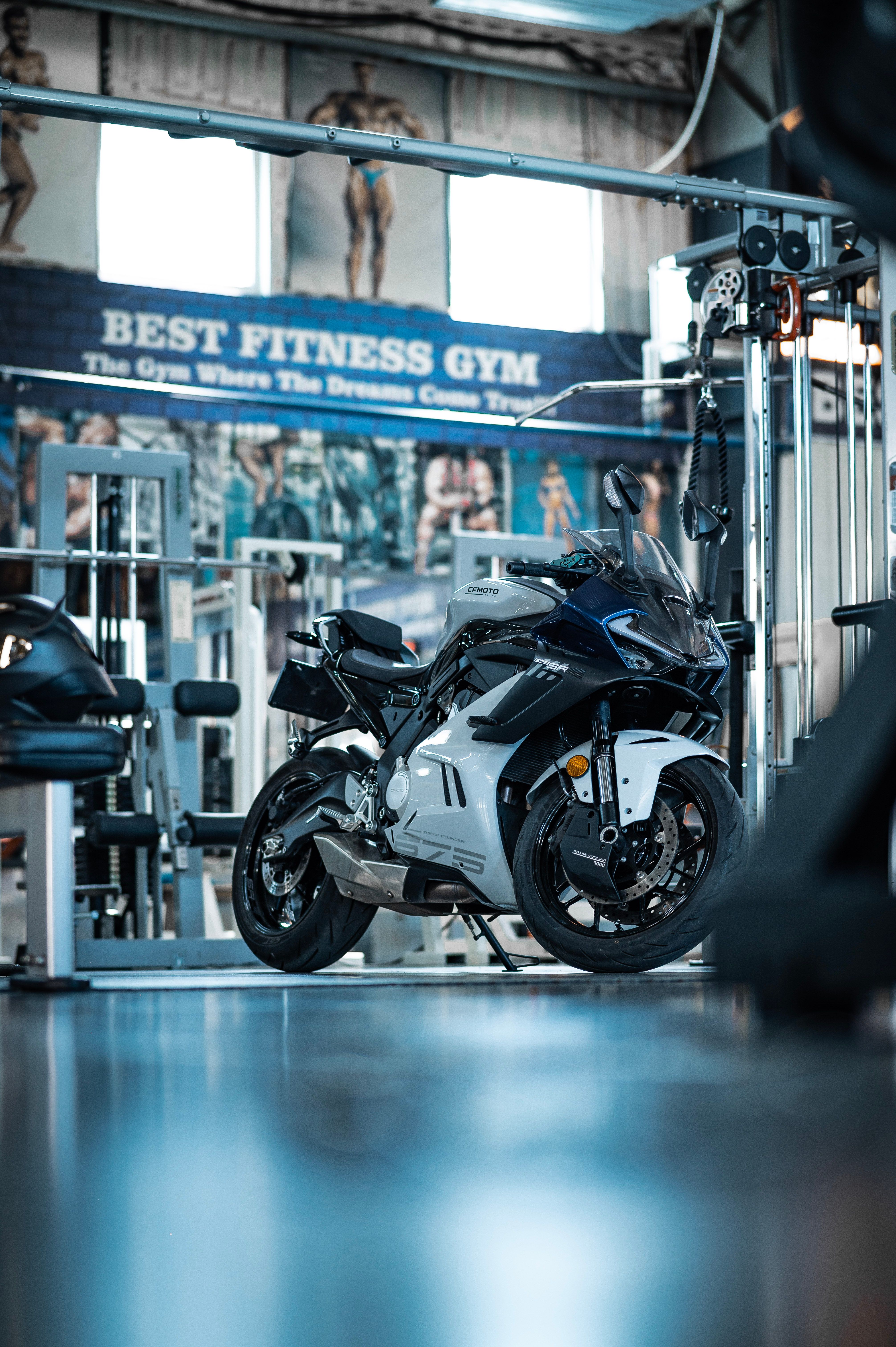 Sleek black motorcycle parked inside a fitness gym showing modern design and contrast.