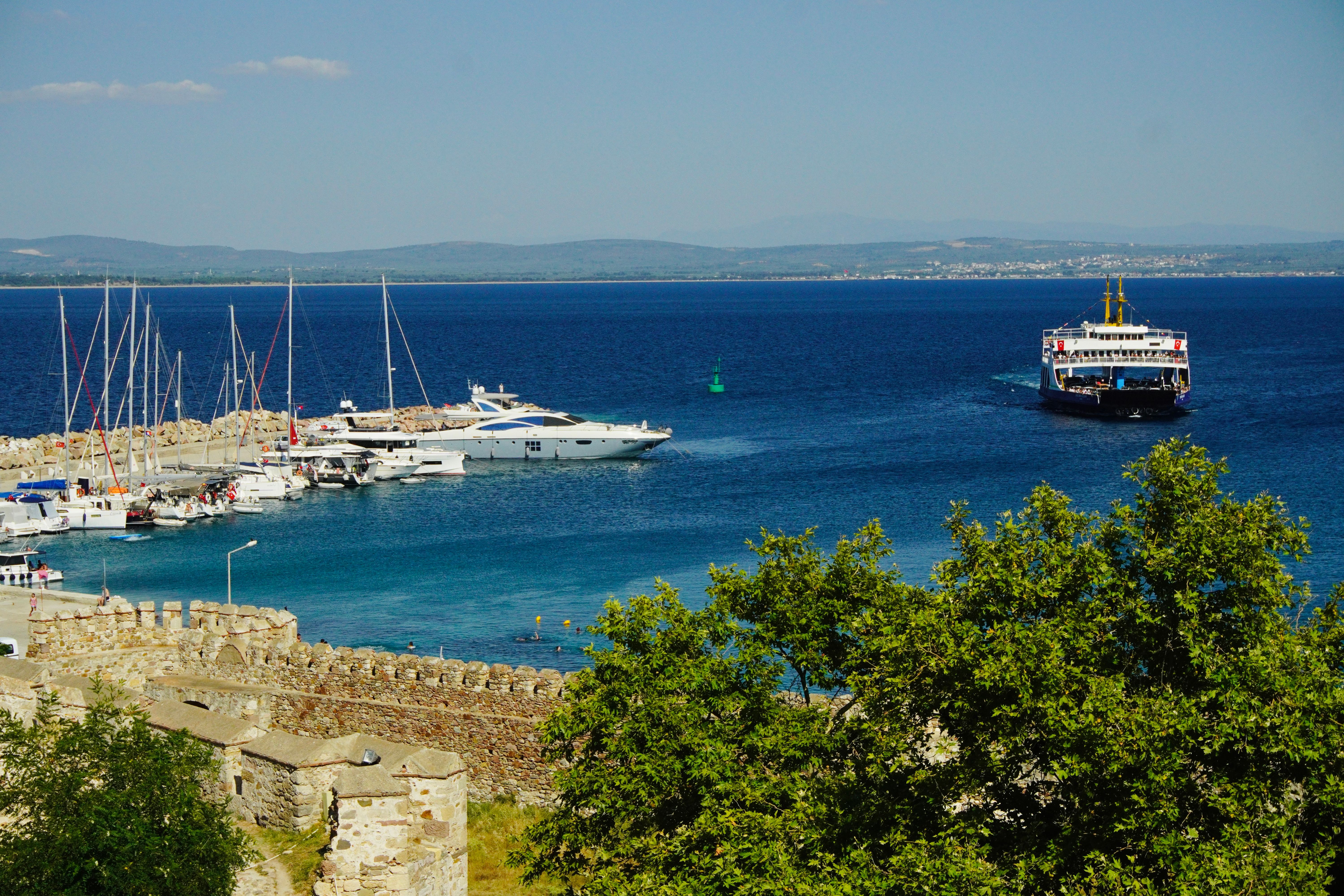 Vibrant harbor scene showcasing yachts docked and a ferry on blue sea.