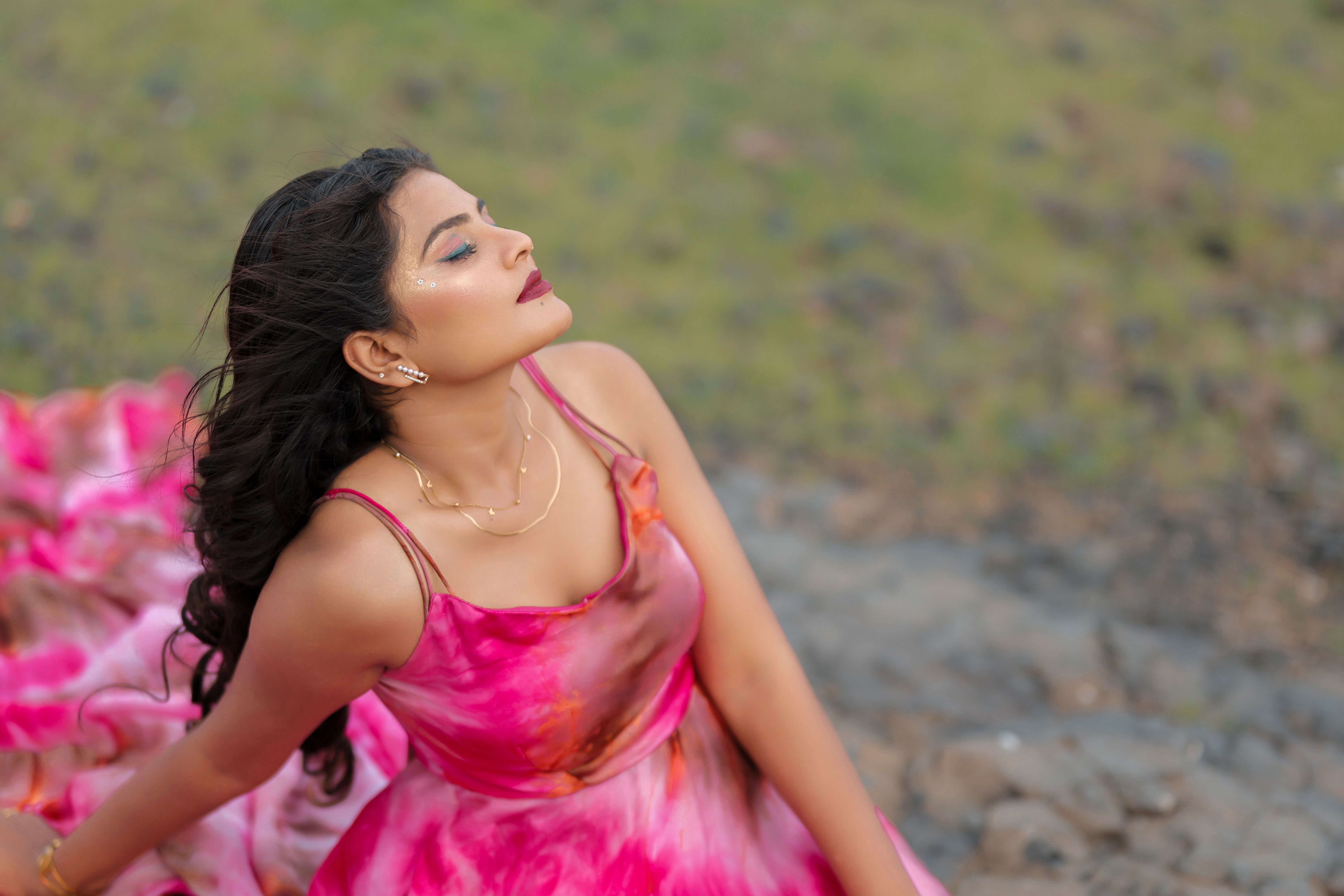 A model in a pink slip dress spinning mid-laugh, hot-pink seamless backdrop