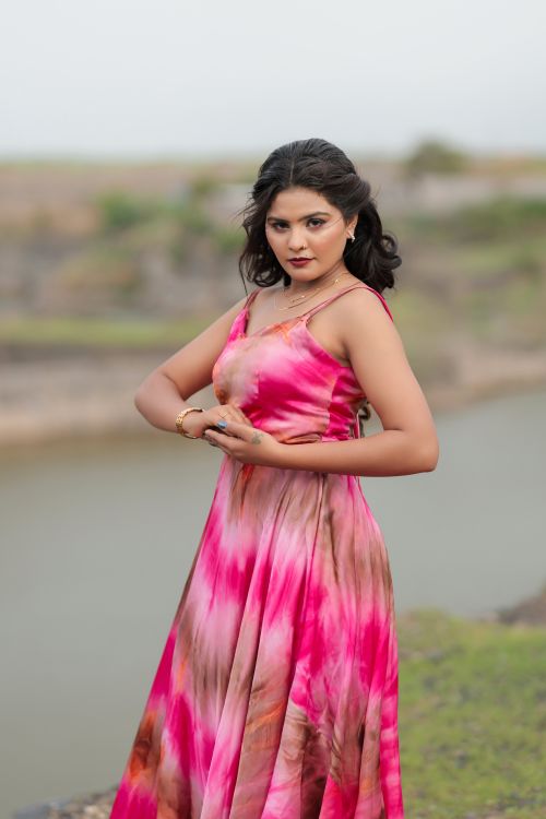 Free A woman in a striking pink dress poses gracefully against a scenic outdoor backdrop, embodying summer elegance. Stock Photo