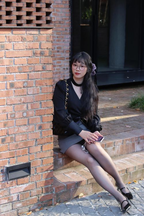 Free Young woman sitting on steps in Nanjing, dressed stylishly with glasses and heels. Stock Photo
