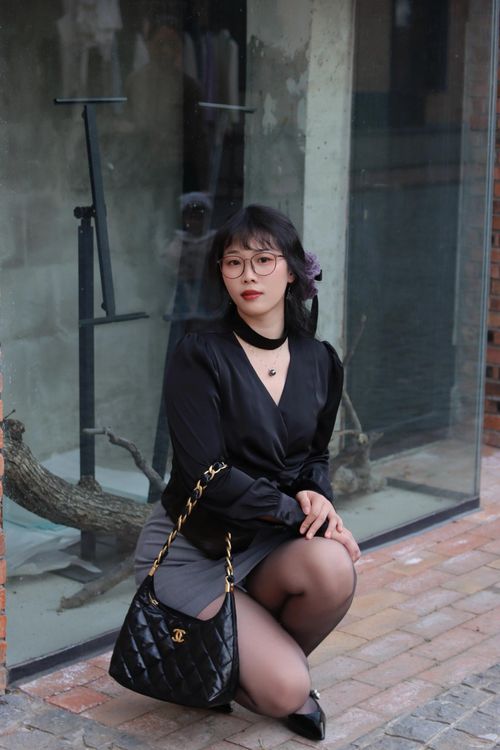 Free Stylish woman posing near a glass wall in Nanjing, China, showcasing a chic black outfit with accessories. Stock Photo