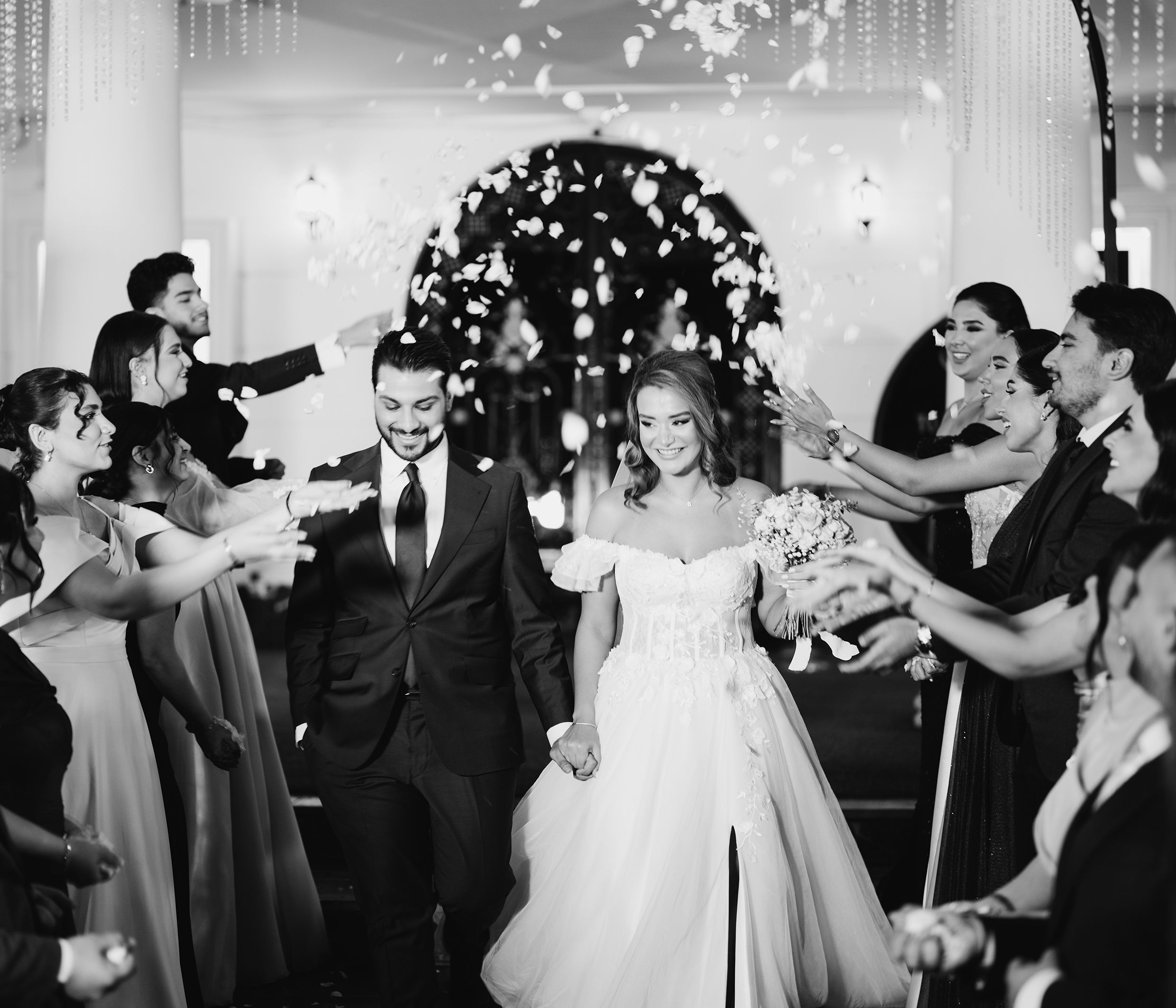 Newlyweds walk through celebratory guests at an elegant wedding ceremony.