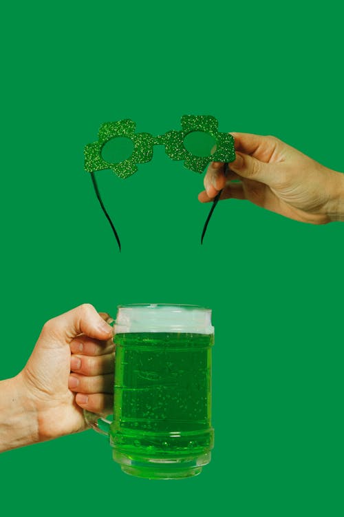 Person Holding Glass Mug and Green Glasses