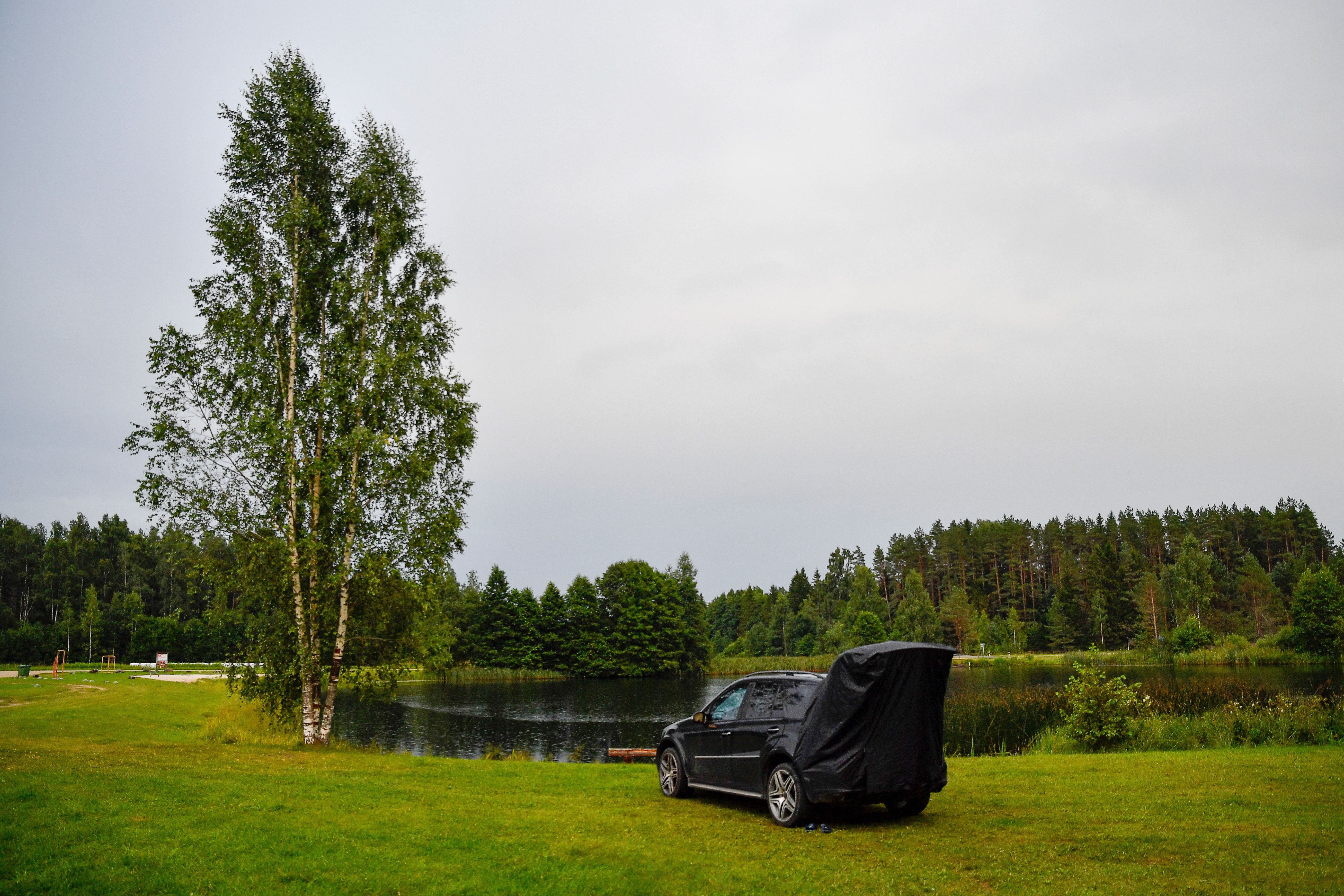 Explore tranquil car camping at a scenic lakeside in Estonia's Rapla region during summer.