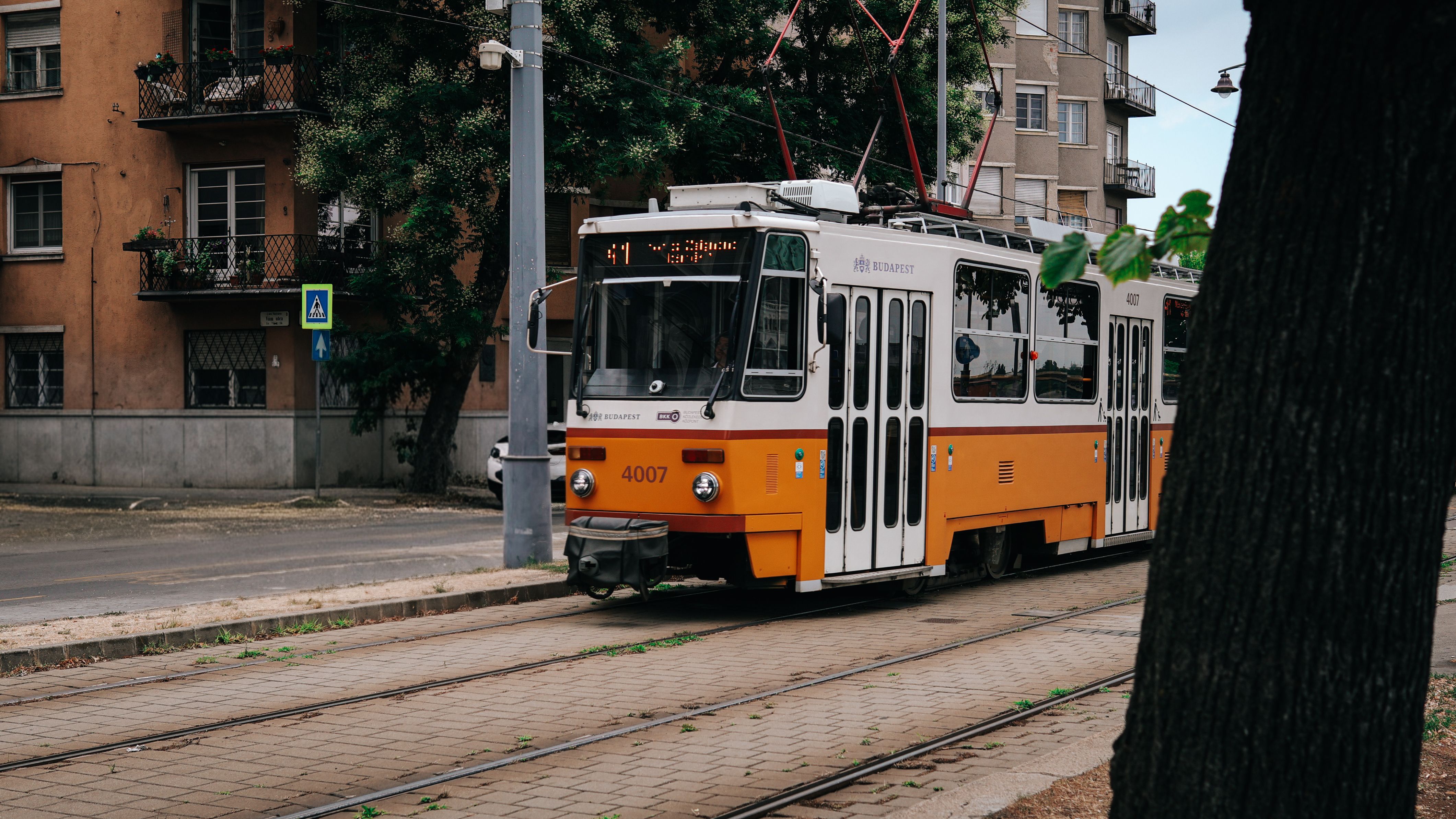 Classic yellow tram in Budapest, Hungary, on a city street amid historic buildings.