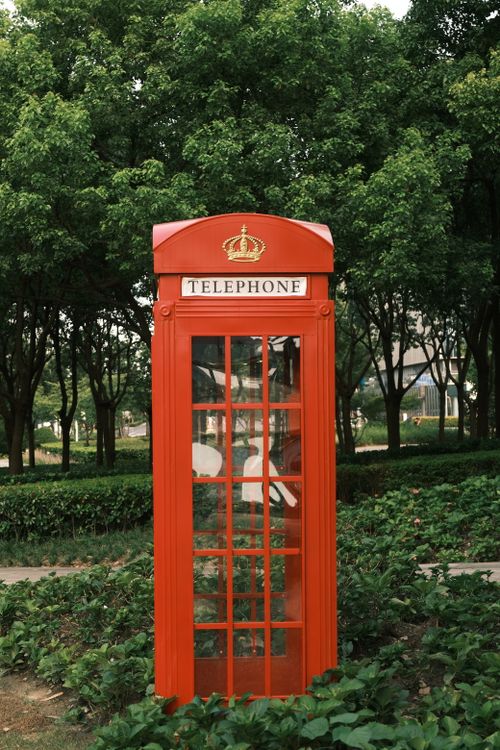 Free Classic red British telephone booth in a lush green park setting. Stock Photo