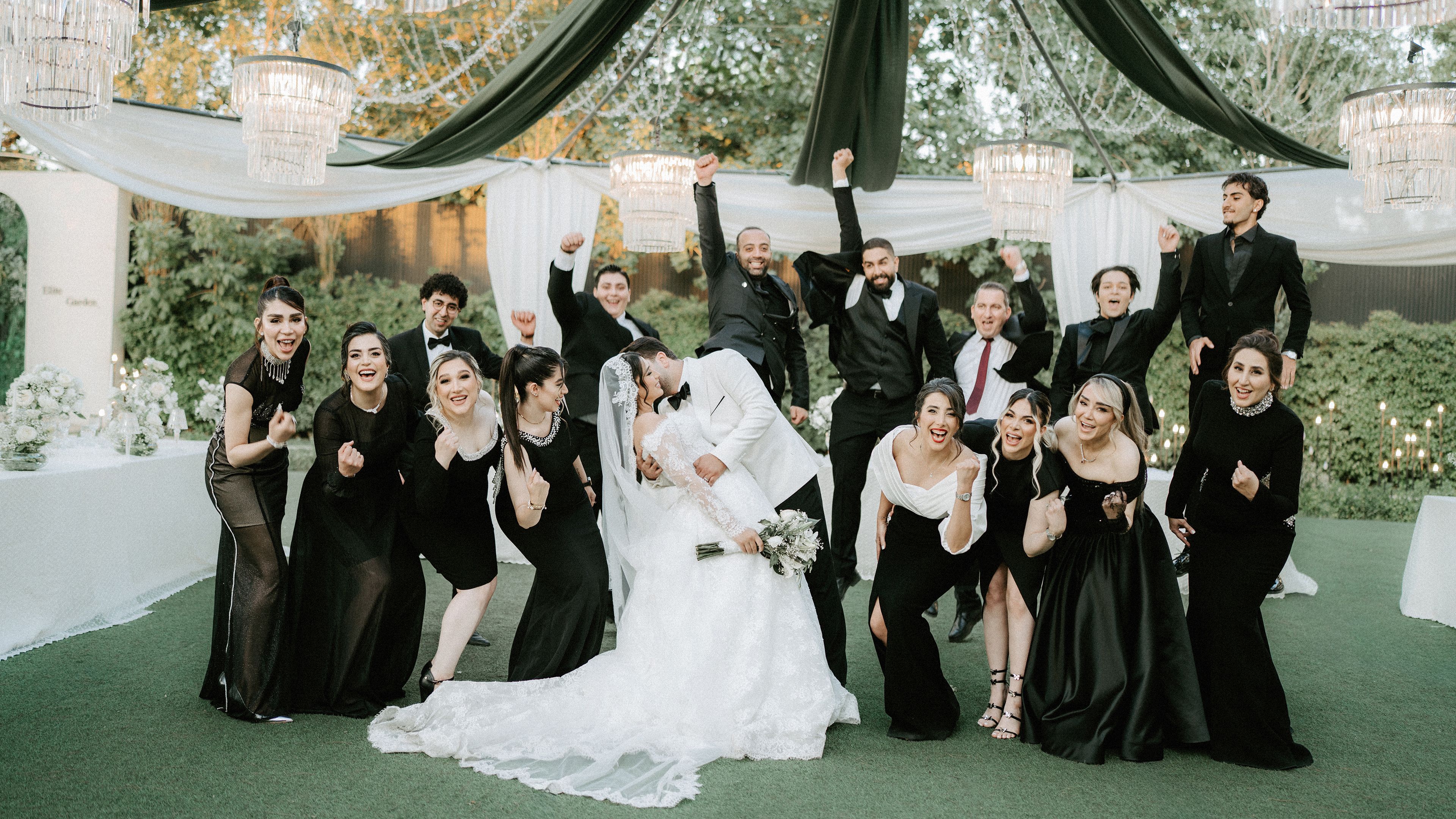 A joyful group photo featuring a bride, groom, and friends celebrating outdoors.
