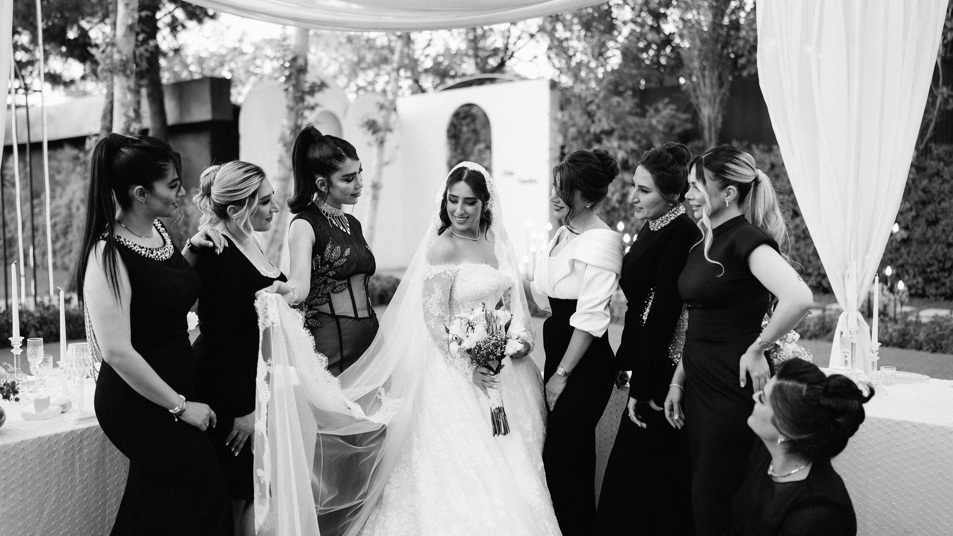 A joyful bride surrounded by her bridesmaids at an outdoor wedding ceremony.