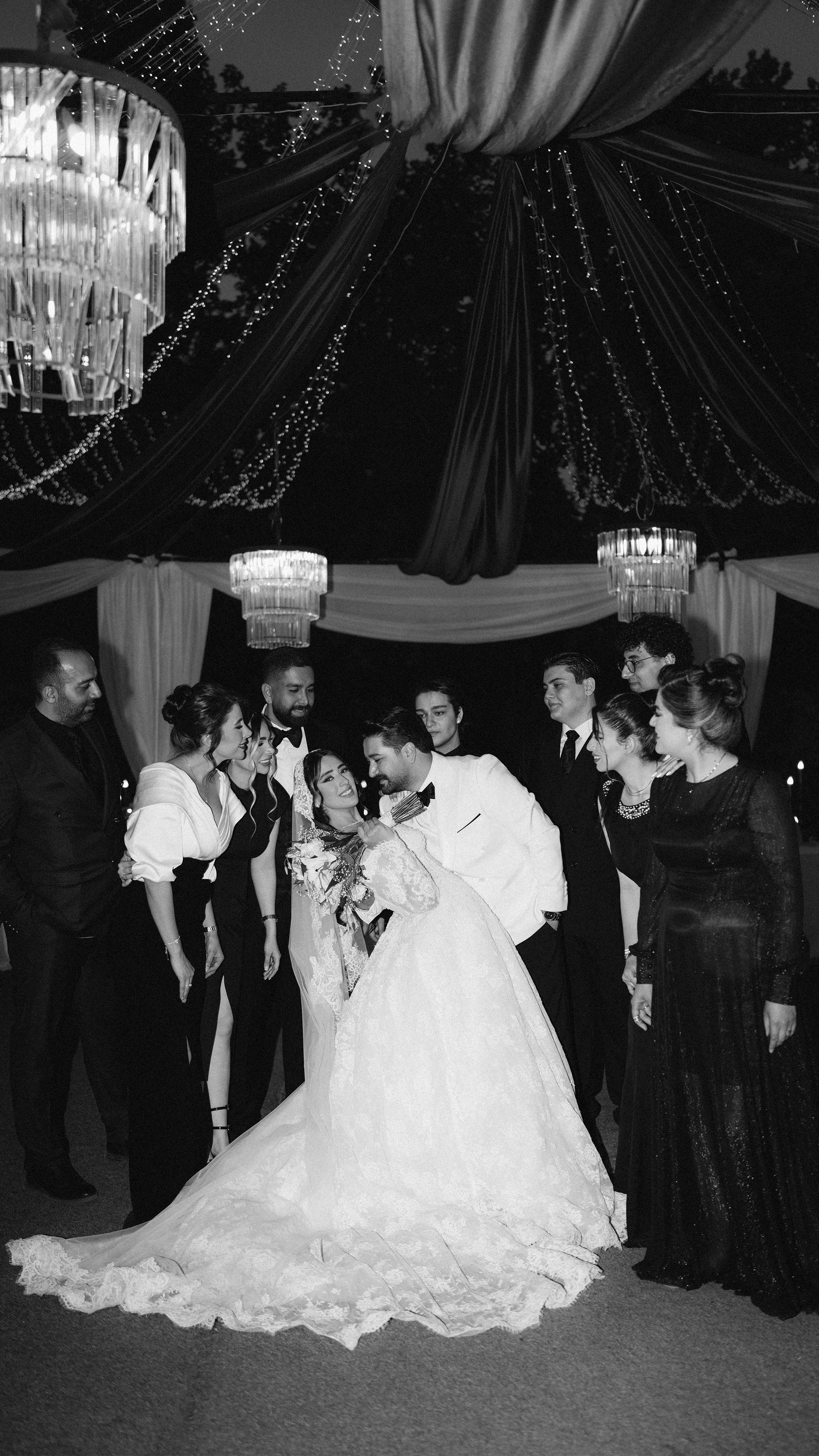 A classic black and white photo of a wedding party celebrating elegantly outdoors.