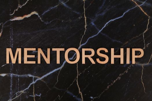 The word 'Mentorship' displayed in wooden letters on a marble surface symbolizing guidance.