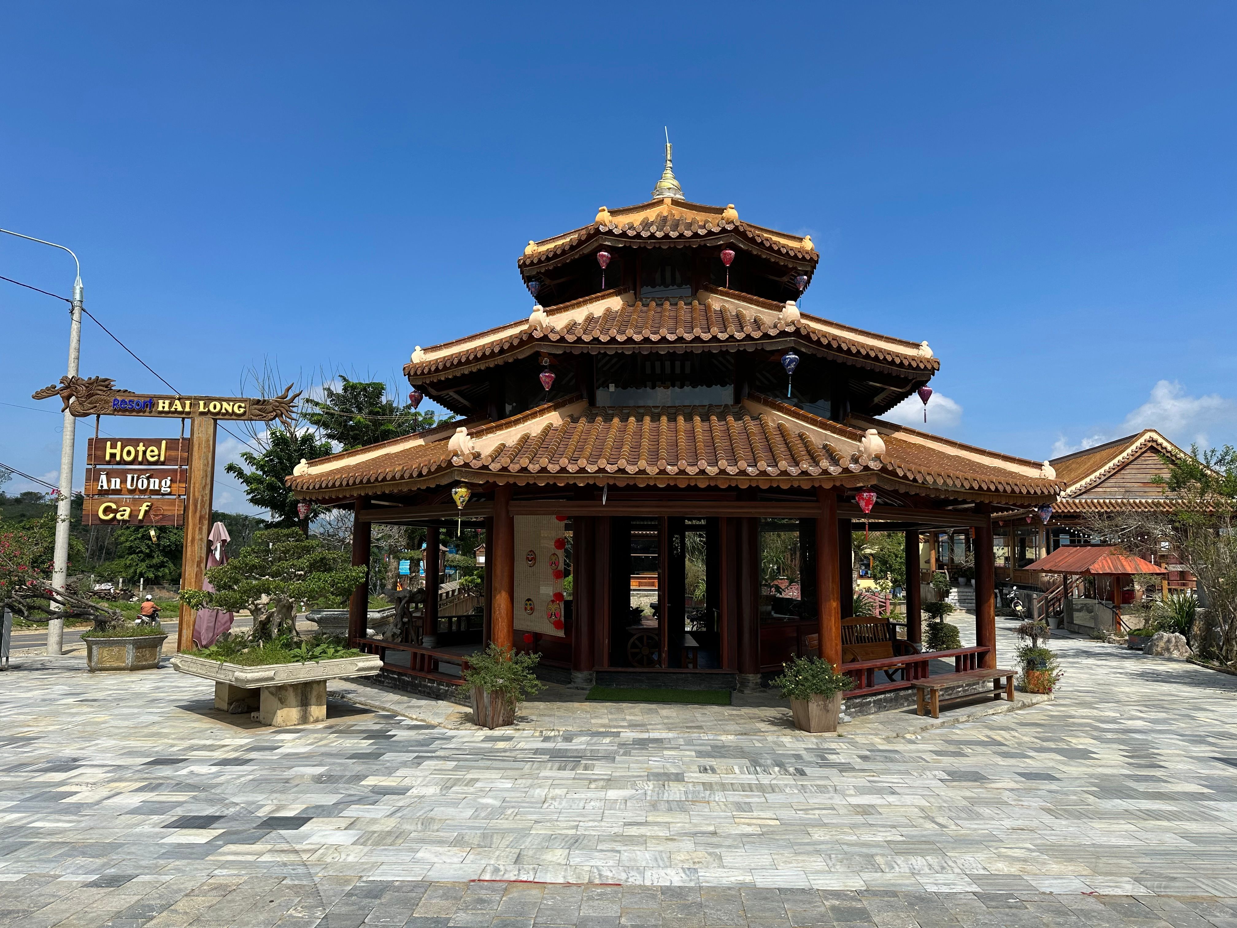 A traditional Vietnamese pagoda with intricate design under a clear blue sky, surrounded by nature and architecture.