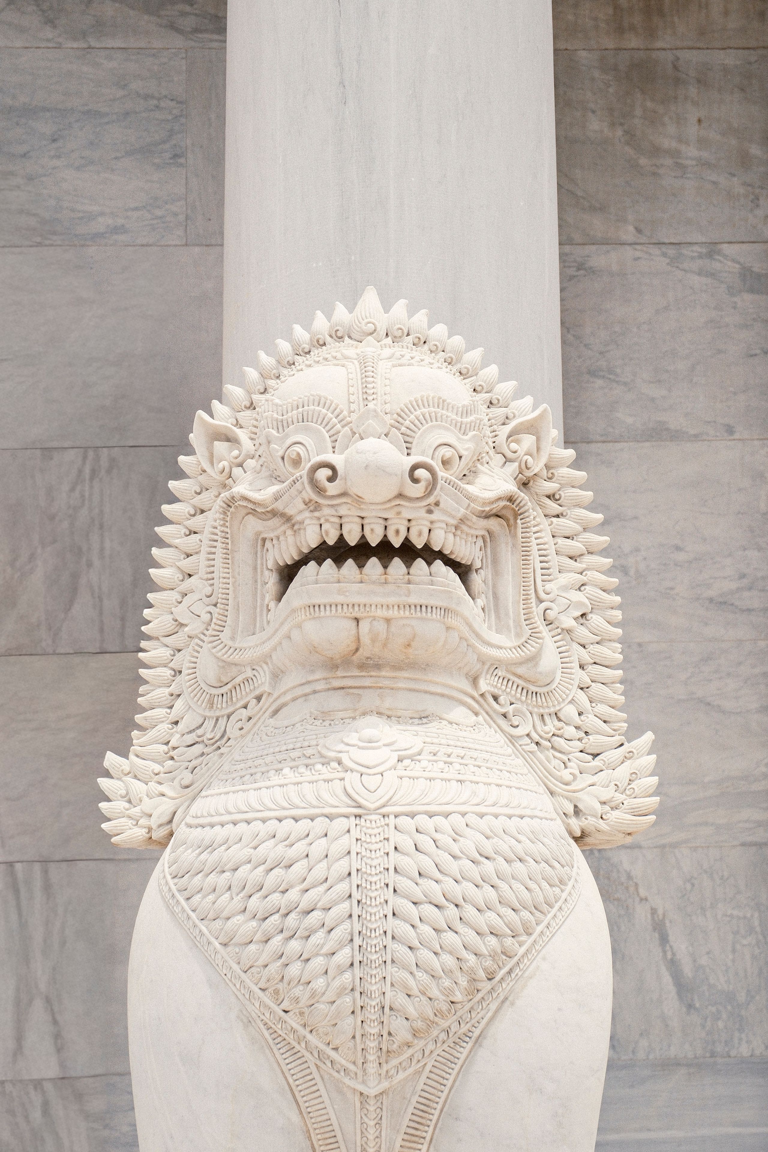Detailed white marble statue of a mythical creature with intricate carvings, temple setting.