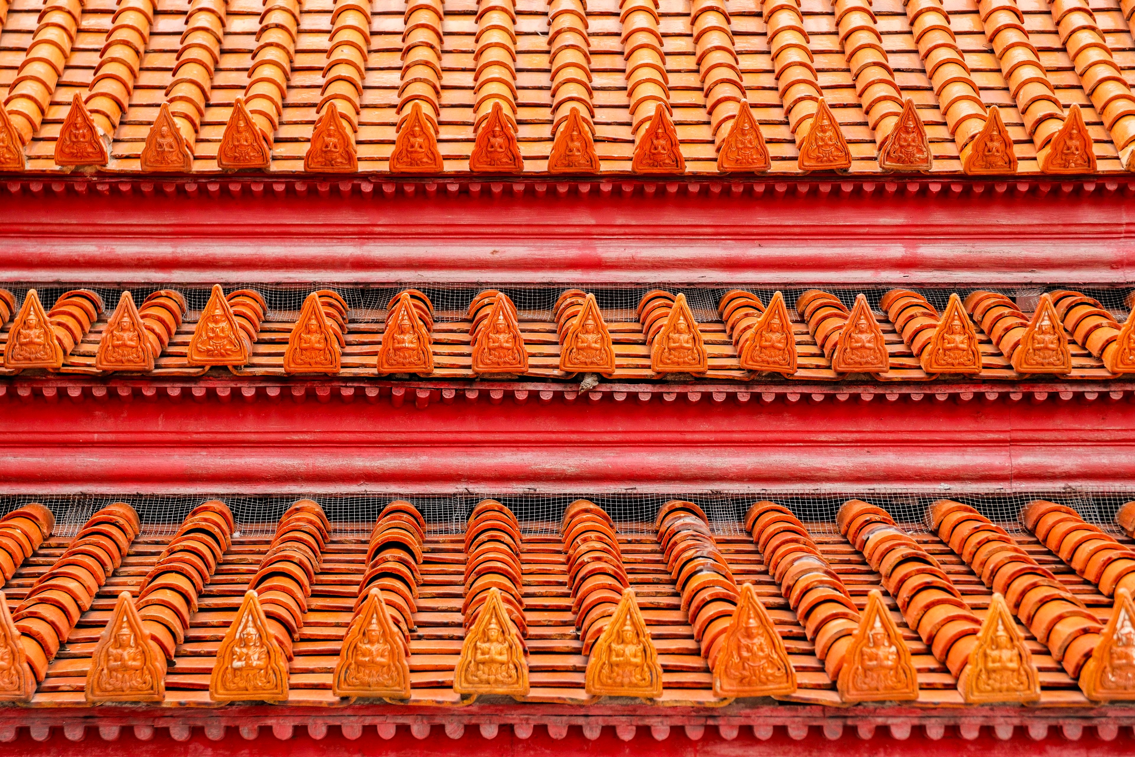 Close-up of a traditional Asian rooftop with vivid red and orange tiles showcasing cultural architectural detail.