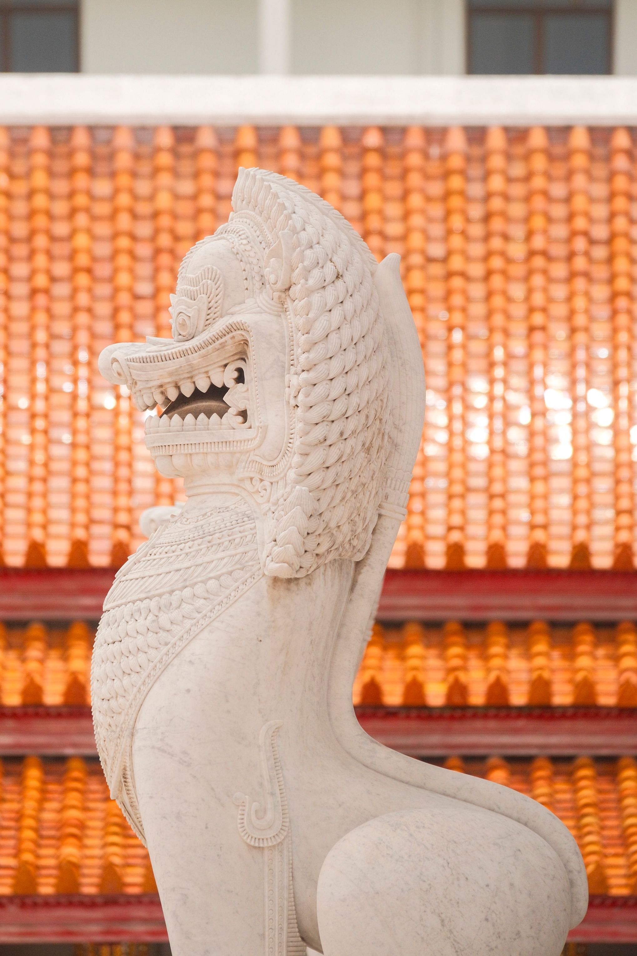 Intricate stone sculpture with temple roof backdrop, showcasing traditional art and architecture.