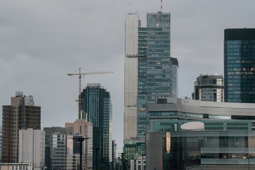 A view of Warsaw skyline featuring contemporary skyscrapers and construction cranes at daytime.