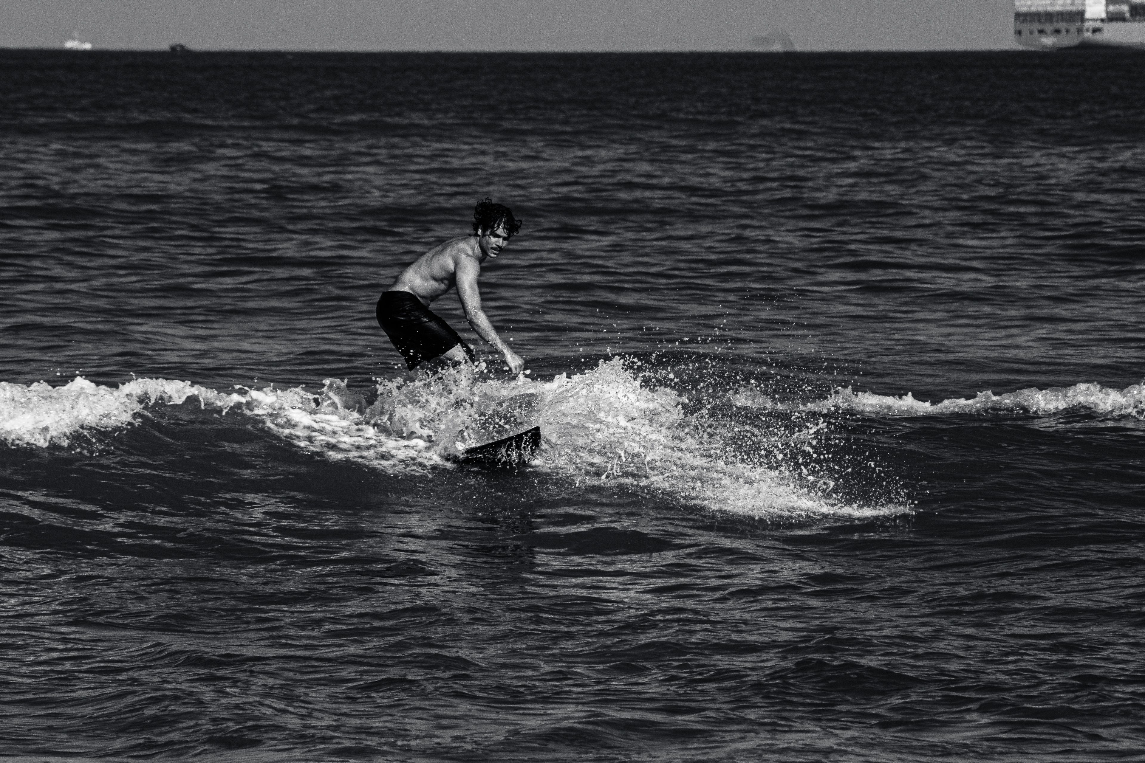 A surfer in action captured in black and white, riding the waves in the ocean.