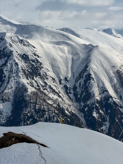 Free Breathtaking view of a snowy mountain range with a solitary figure, ideal for winter adventure themes. Stock Photo