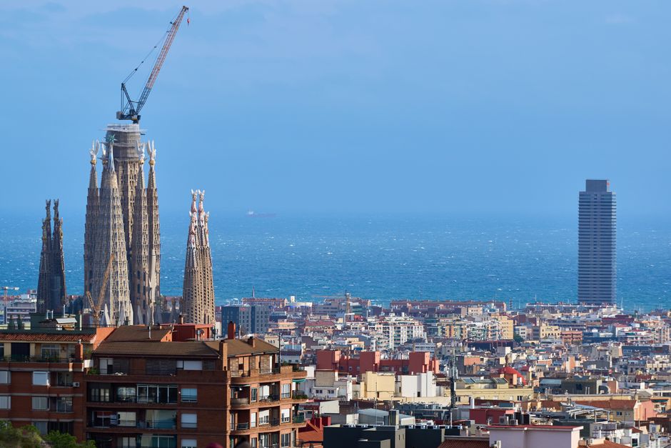 Una vista panorámica de Barcelona con la Sagrada Familia y el mar Mediterráneo al fondo.
