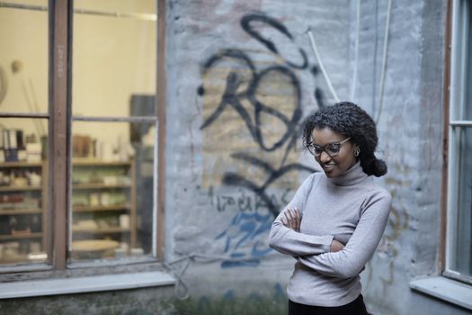 Young woman smiling in front of an urban graffiti wall, exuding confidence.