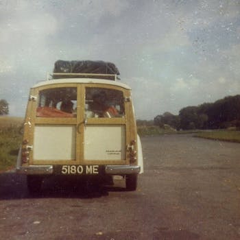 A classic Morris Minor Traveler loaded for a road trip, parked outdoors.