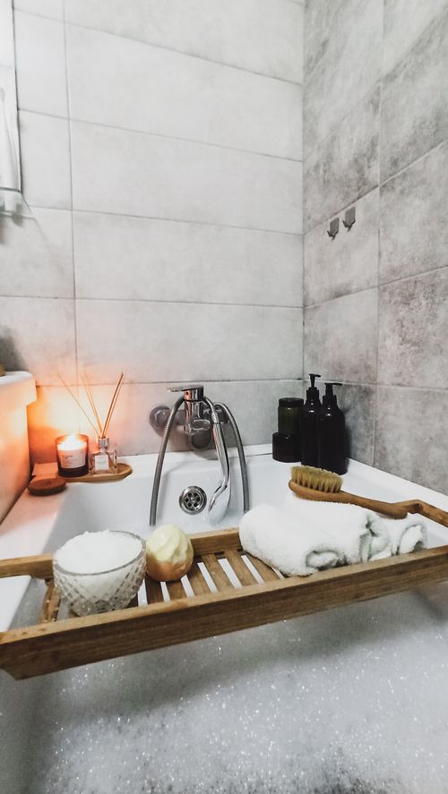 Free Cozy bathroom setting with relaxing candlelight and bath essentials on a wooden tray. Stock Photo