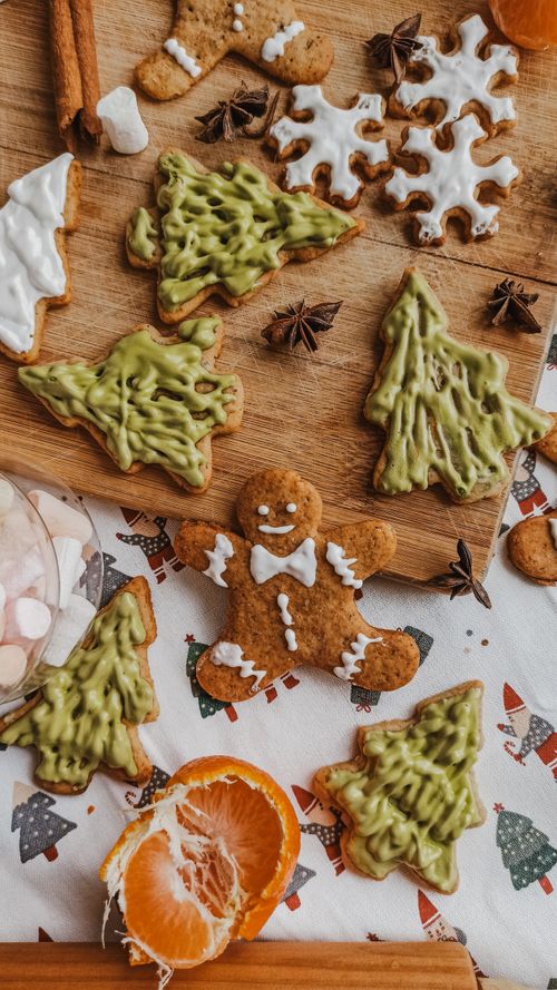 Free Christmas-themed gingerbread cookies with green icing and citrus fruit arranged on a festive table. Stock Photo