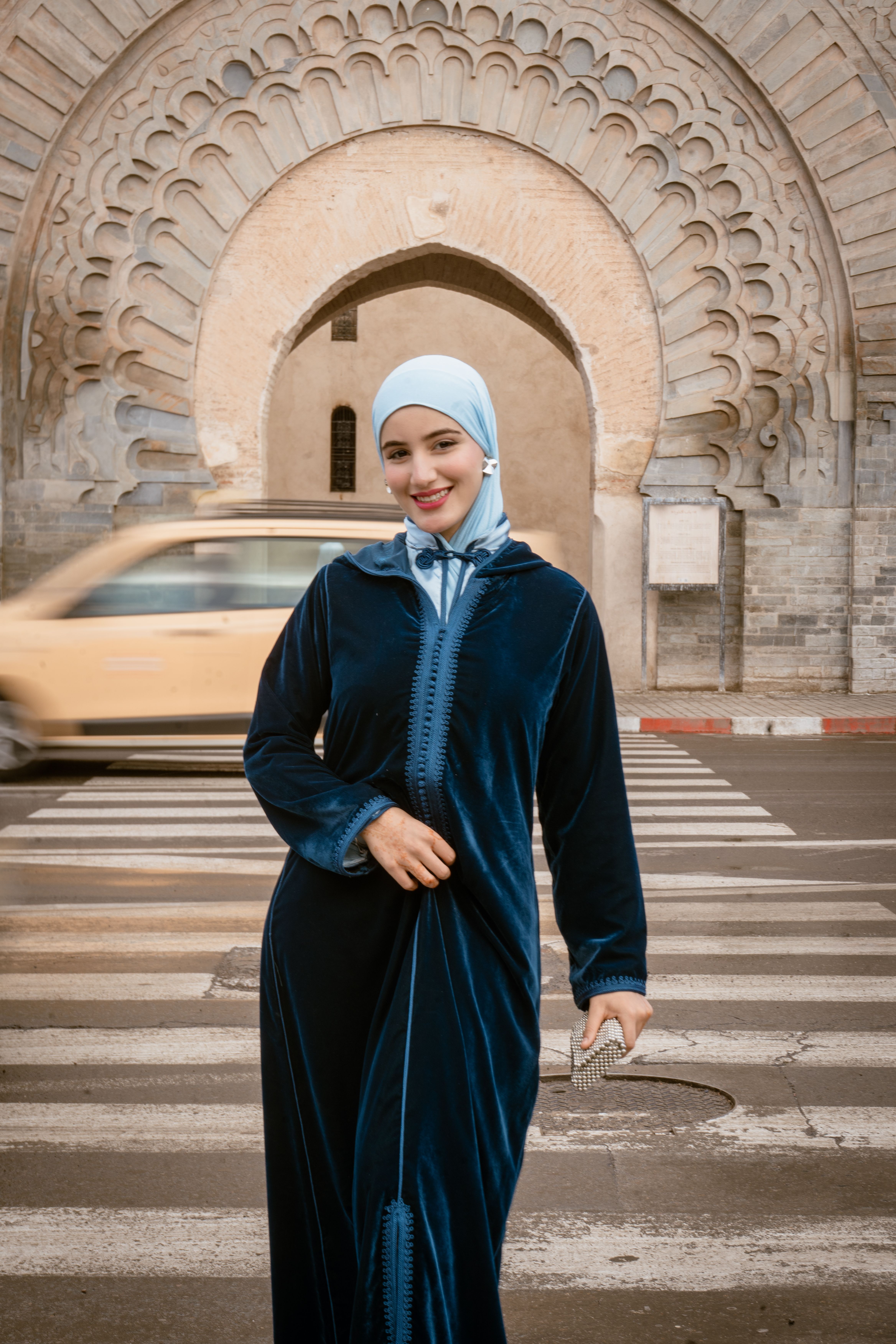 Woman in a blue djellaba with a hijab stands confidently in Marrakesh, Morocco.