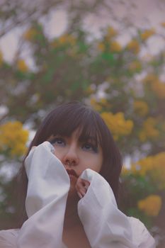 一张在户外拍摄的女人宁静肖像，背景是黄色的花朵