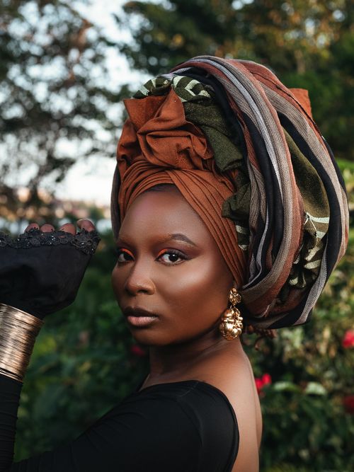 Free Elegant outdoor portrait of a woman in traditional headwrap and jewelry. Stock Photo